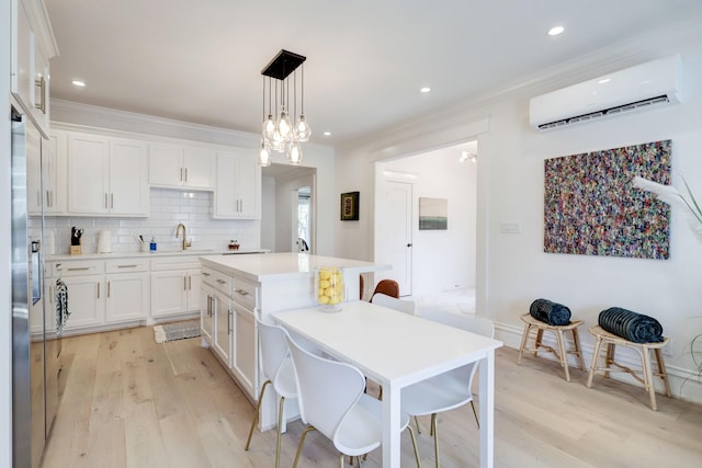 kitchen with a center island, white cabinets, stainless steel refrigerator with ice dispenser, decorative light fixtures, and a wall unit AC