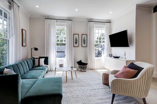 living room with light hardwood / wood-style flooring, a wealth of natural light, and ornamental molding