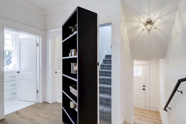 hallway with light wood-type flooring, plenty of natural light, and crown molding