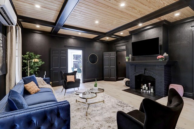 living room featuring a fireplace, coffered ceiling, a wall unit AC, light hardwood / wood-style flooring, and beamed ceiling