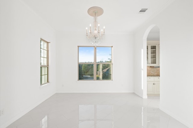 unfurnished room featuring ornamental molding and a notable chandelier