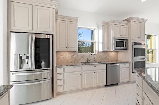 kitchen with backsplash, sink, stainless steel appliances, and stone countertops