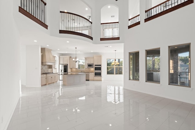 unfurnished living room featuring a chandelier, a towering ceiling, and light tile patterned flooring