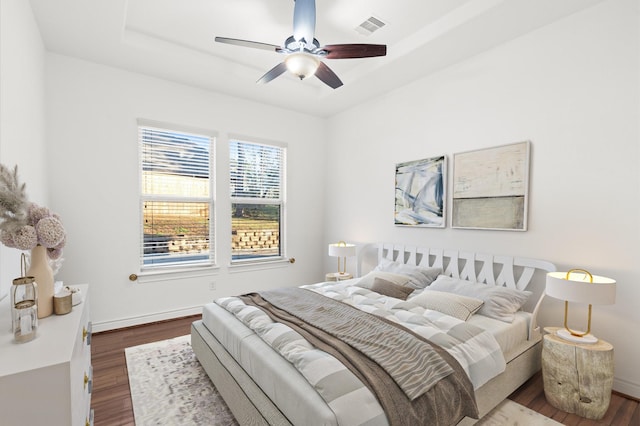 bedroom featuring hardwood / wood-style floors, a tray ceiling, and ceiling fan