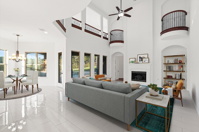 tiled living room featuring ceiling fan with notable chandelier and a high ceiling