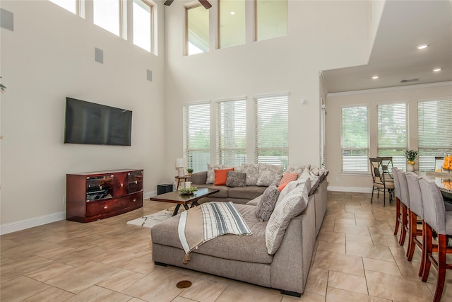 living room with a high ceiling, ornamental molding, and light tile patterned flooring