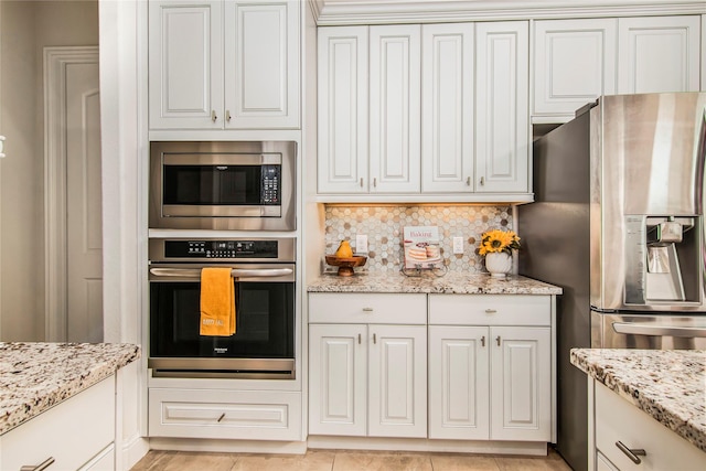 kitchen featuring backsplash, white cabinetry, light stone counters, and appliances with stainless steel finishes