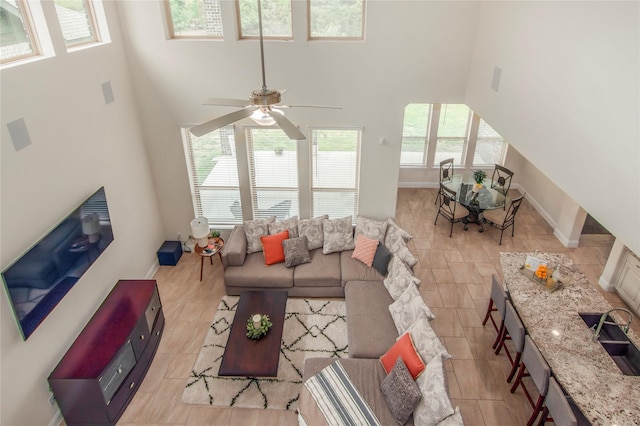 living room with a towering ceiling and ceiling fan