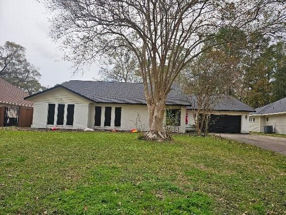 ranch-style house with cooling unit, a front yard, and a garage