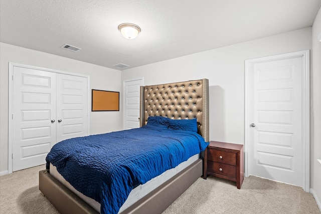 bedroom with a textured ceiling, light colored carpet, and a closet