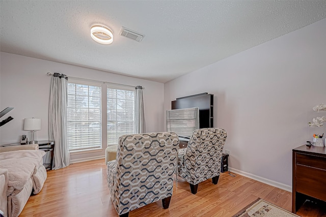 living area featuring light wood-type flooring and a textured ceiling