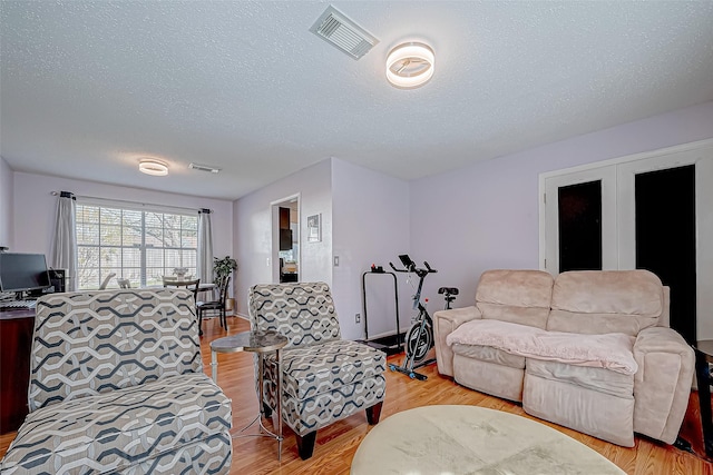 living room featuring a textured ceiling and light wood-type flooring