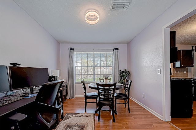 dining area featuring a textured ceiling and light hardwood / wood-style flooring