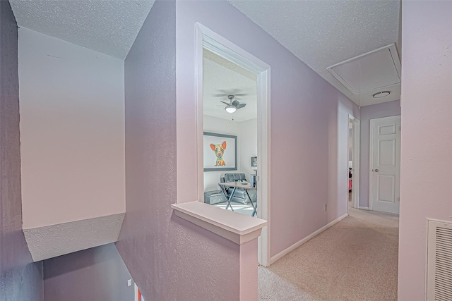 corridor with light colored carpet and a textured ceiling