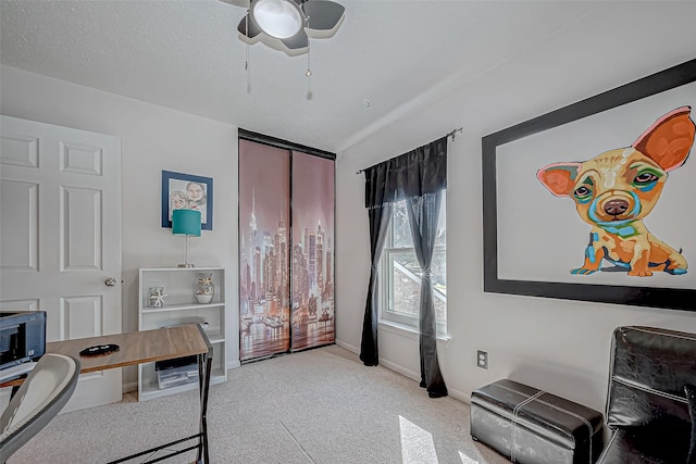 office featuring light carpet, ceiling fan, and a textured ceiling