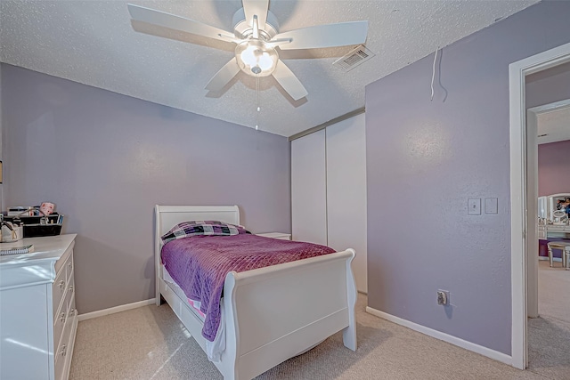 carpeted bedroom featuring ceiling fan and a textured ceiling