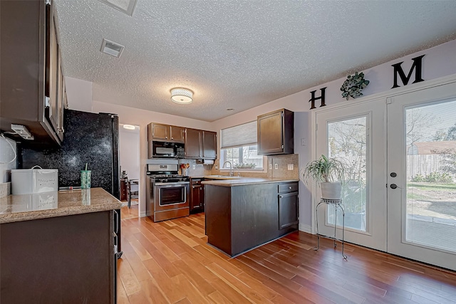 kitchen featuring decorative backsplash, french doors, stainless steel stove, and light hardwood / wood-style floors