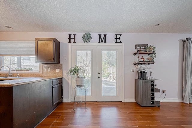 doorway to outside featuring a textured ceiling, sink, dark wood-type flooring, and french doors