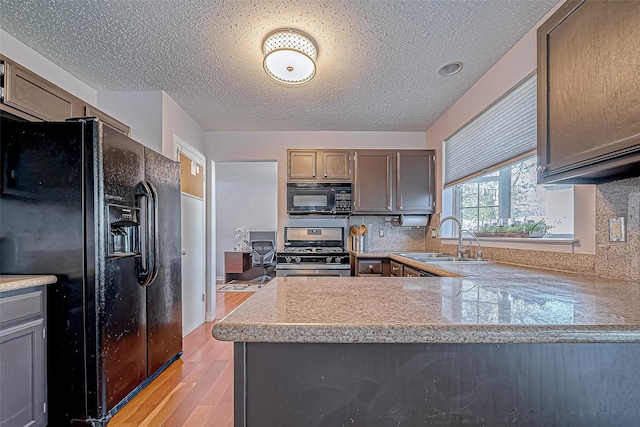 kitchen featuring black appliances, sink, light hardwood / wood-style flooring, decorative backsplash, and kitchen peninsula