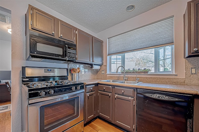 kitchen with backsplash, a textured ceiling, sink, black appliances, and light hardwood / wood-style floors