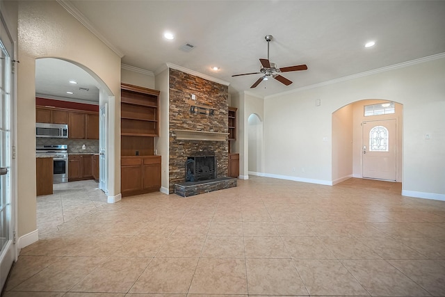 3815 Founders Dr, Needville, TX 77461 - unfurnished living room with ceiling fan, ornamental molding, arched walkways, a stone fireplace, and light tile patterned floors