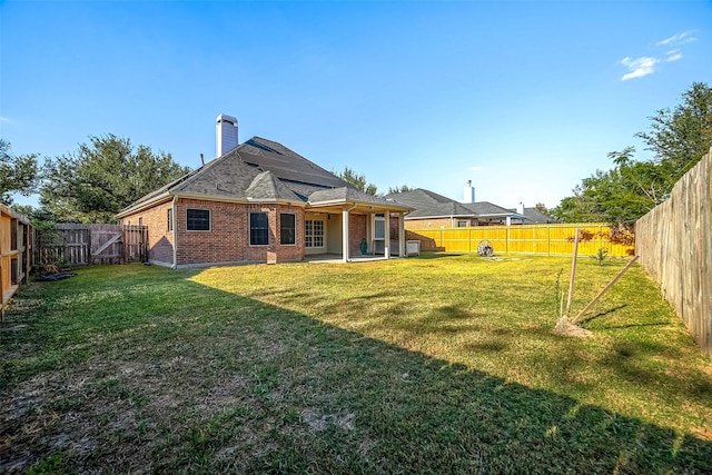 3815 Founders Dr, Needville, TX 77461 - back of property featuring brick siding, a fenced backyard, a chimney, and a patio area