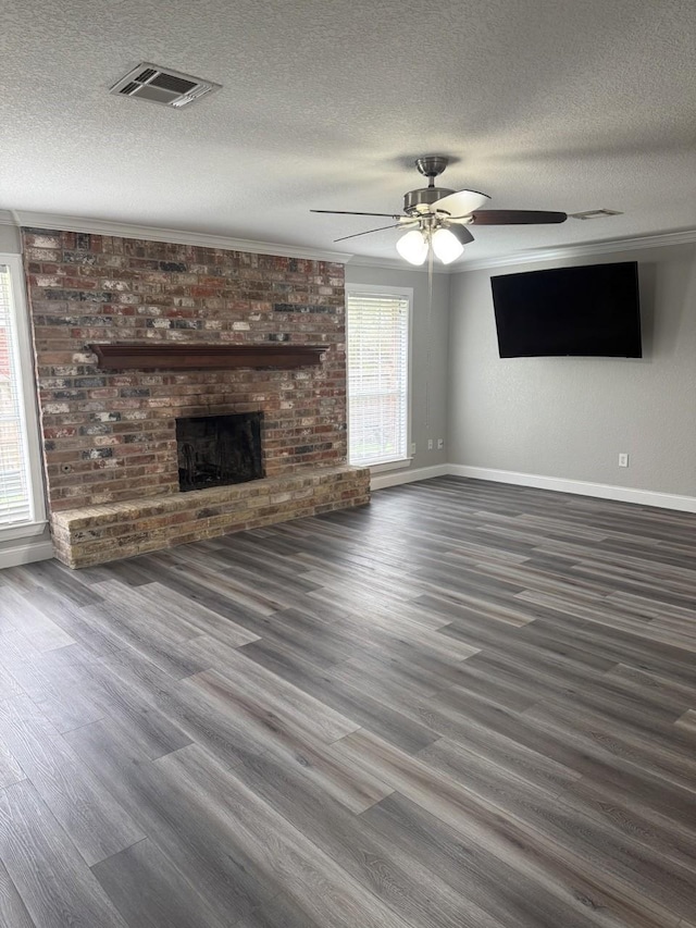 unfurnished living room with ceiling fan, ornamental molding, a textured ceiling, and a brick fireplace