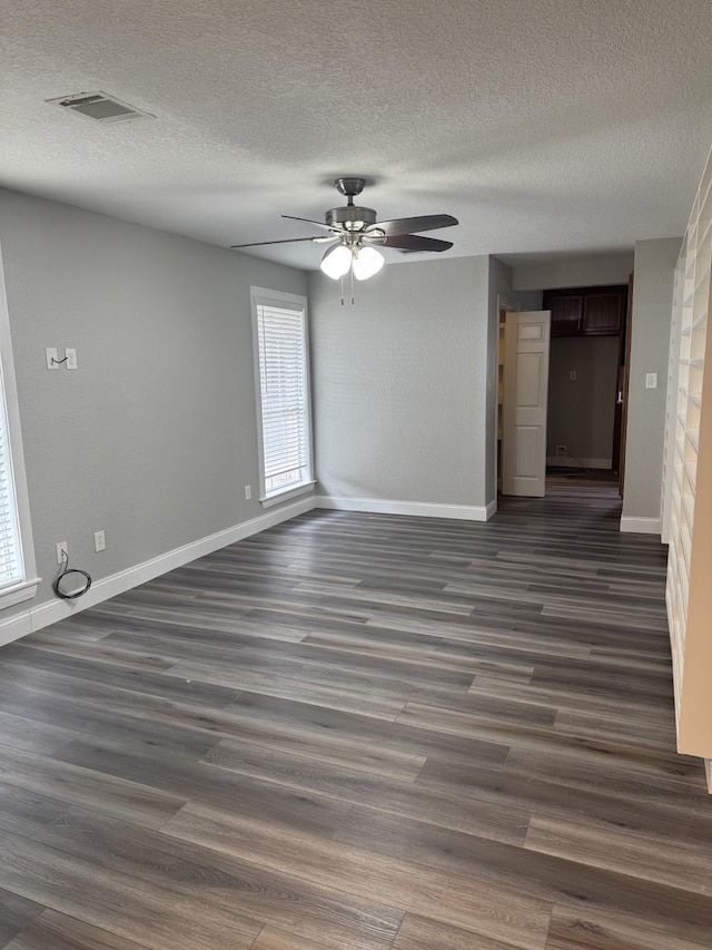 empty room featuring a textured ceiling, dark hardwood / wood-style flooring, and ceiling fan