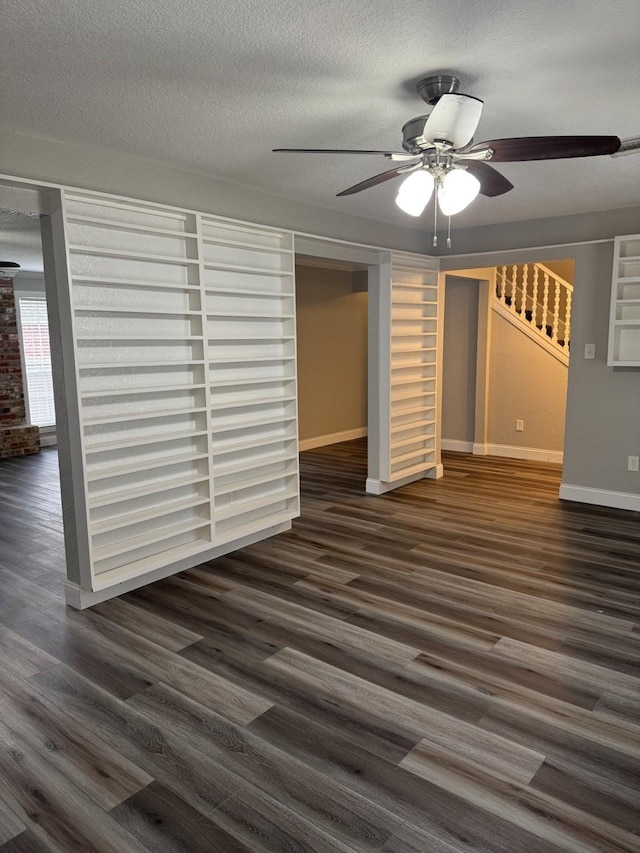 unfurnished living room featuring ceiling fan, dark hardwood / wood-style flooring, and a textured ceiling