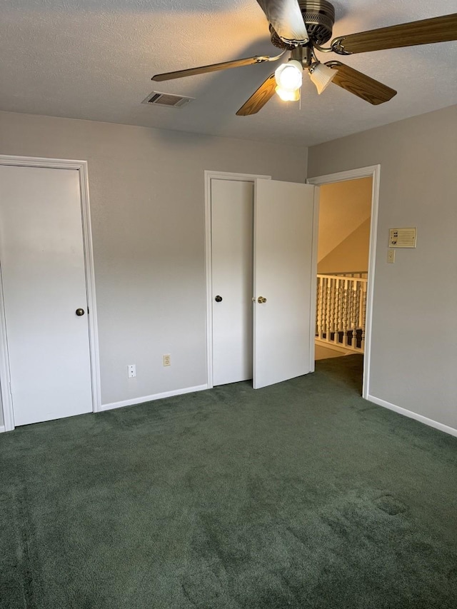 unfurnished bedroom with ceiling fan, dark carpet, and a textured ceiling