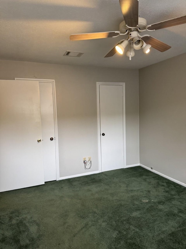 unfurnished bedroom with dark carpet and ceiling fan