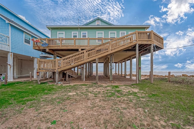 rear view of house with a lawn and a deck with water view