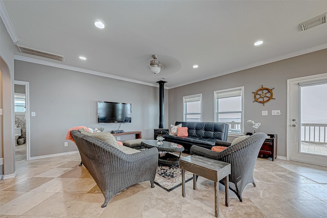 living room with a wood stove, ceiling fan, and ornamental molding