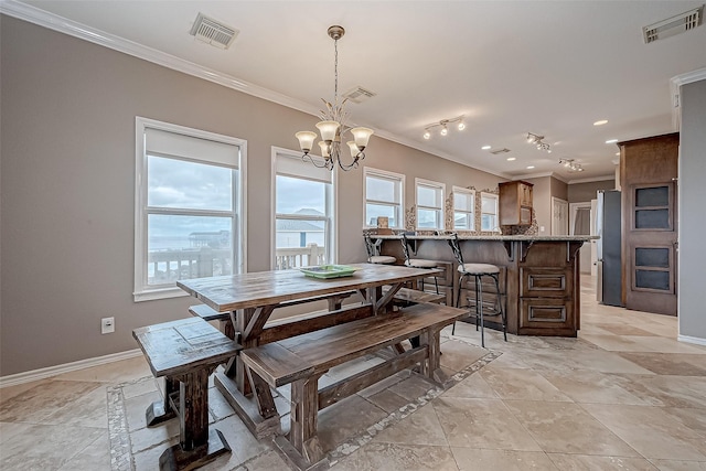 tiled dining room featuring an inviting chandelier and ornamental molding