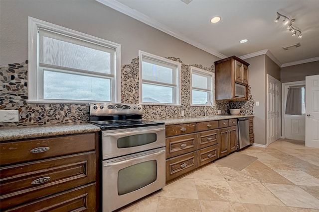 kitchen with crown molding, sink, rail lighting, appliances with stainless steel finishes, and tasteful backsplash