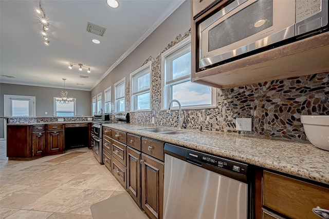 kitchen featuring appliances with stainless steel finishes, ornamental molding, sink, a notable chandelier, and hanging light fixtures