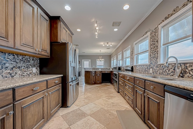 kitchen with backsplash, light stone counters, ornamental molding, stainless steel appliances, and sink