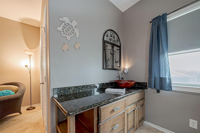 interior space featuring sink, dark stone counters, and light tile patterned flooring