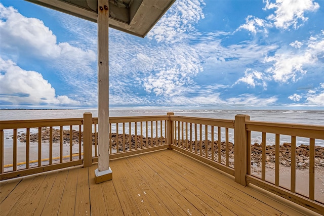 wooden terrace featuring a water view and a view of the beach