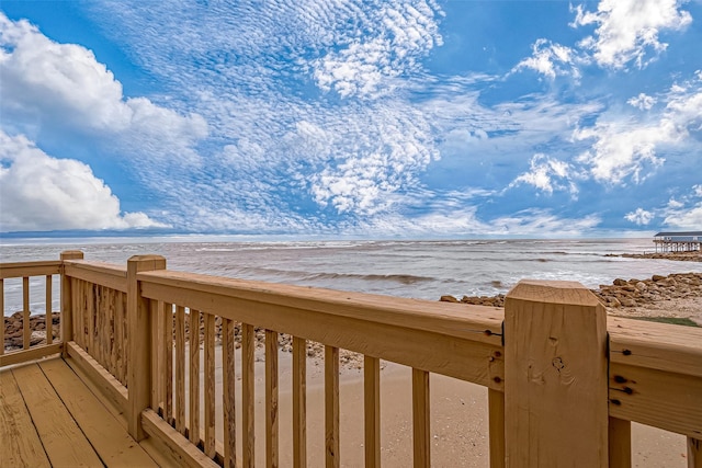 wooden terrace featuring a water view and a beach view