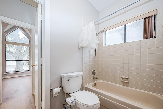 bathroom featuring hardwood / wood-style flooring, tiled shower / bath combo, and toilet