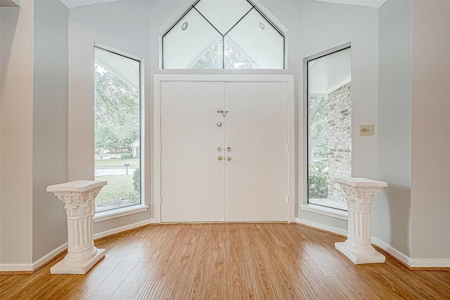 entryway with lofted ceiling, light wood-type flooring, and a wealth of natural light