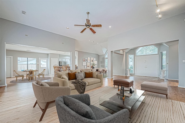 living room with ceiling fan, vaulted ceiling, and light wood-type flooring