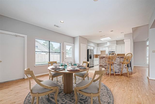 dining area with a skylight and light wood-type flooring