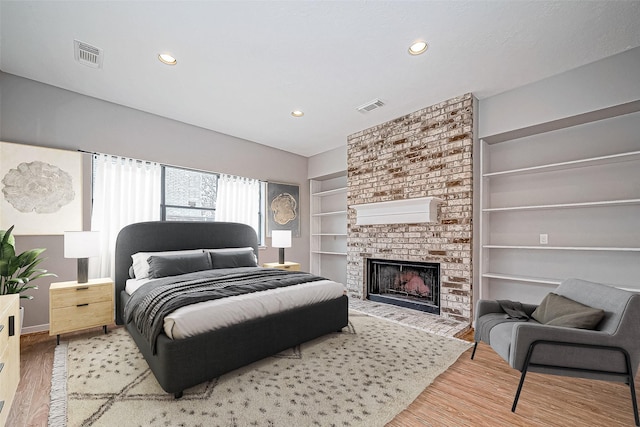 bedroom featuring hardwood / wood-style flooring and a brick fireplace