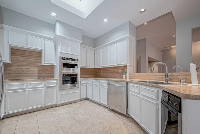 kitchen featuring light tile patterned floors, stainless steel appliances, and white cabinetry