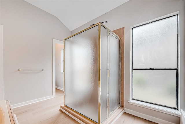 bathroom featuring hardwood / wood-style flooring, lofted ceiling, and a shower with door