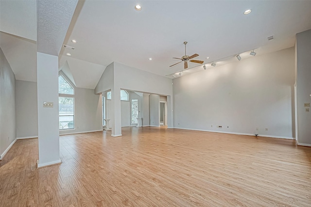 unfurnished living room with ceiling fan, rail lighting, lofted ceiling, and light wood-type flooring