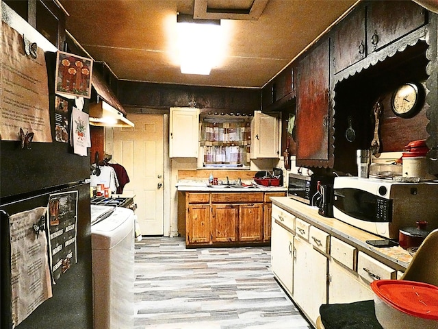 kitchen with light wood-type flooring, sink, and exhaust hood