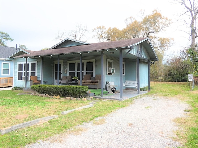 bungalow-style home with cooling unit, covered porch, and a front yard